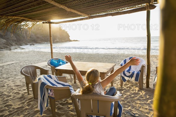 Caucasian girl with arms raised in chair at beach