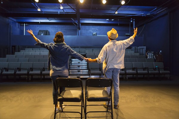 Caucasian actors rehearsing waving in theater