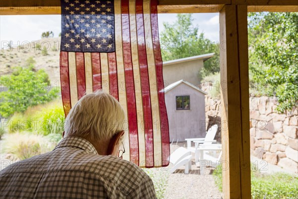 Caucasian man near American flag in the backyard