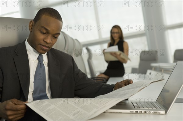 African businessman reading newspaper in conference room