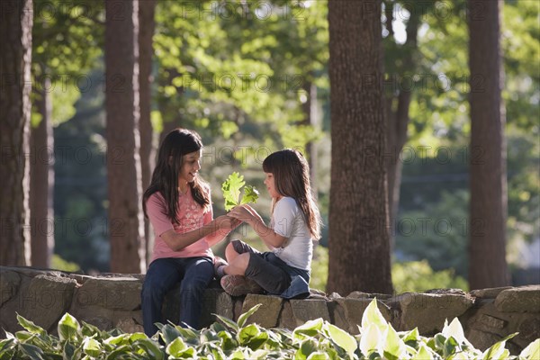 Hispanic sisters holding leaf