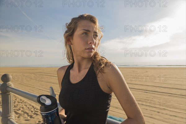 Caucasian teenage girl leaning on railing at beach