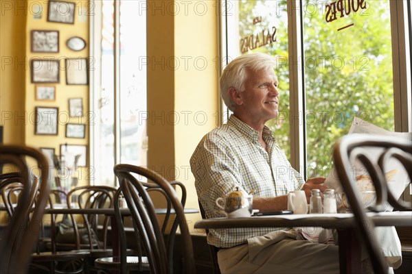 Caucasian man reading newspaper in restaurant