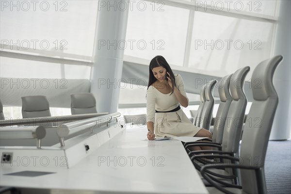 Mixed race businesswoman on cell phone in conference room