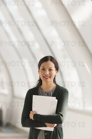 Japanese businesswoman carrying papers in lobby