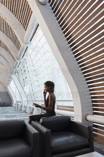 Black businesswomen reading paperwork using cell phone