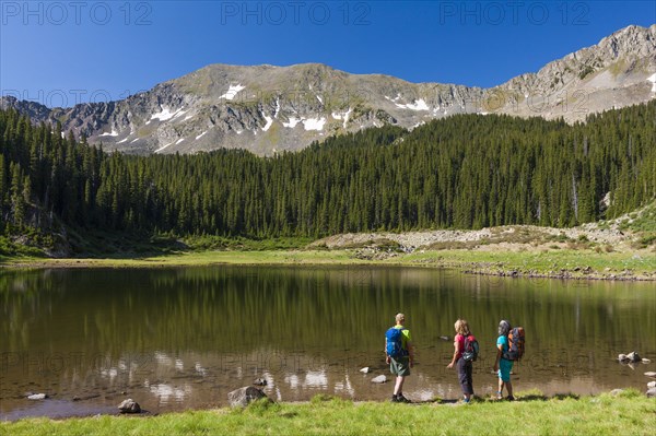 Hikers admiring still lake in rural landscape
