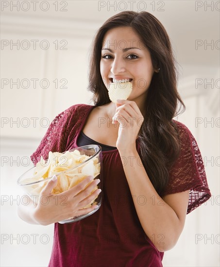 Mixed race woman eating potato chips