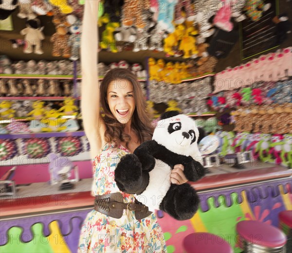 Caucasian woman holding stuffed animal at carnival