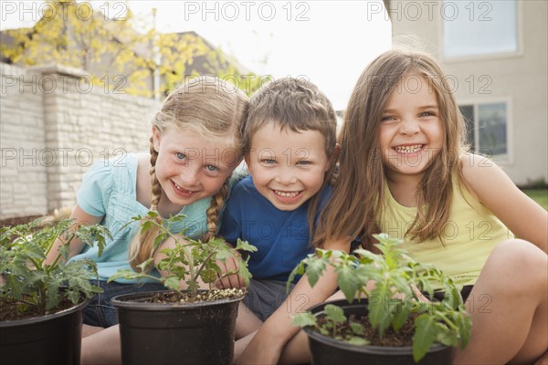 Caucasian children gardening in backyard