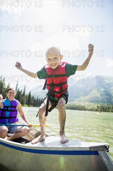 Caucasian boy standing on canoe on lake