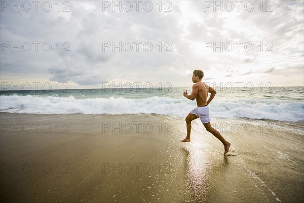 Caucasian man running on beach