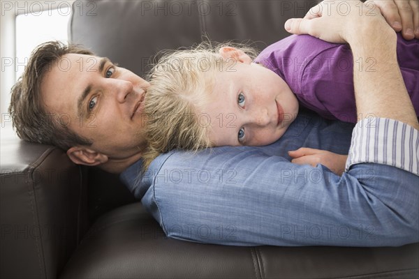 Caucasian father and daughter relaxing on sofa