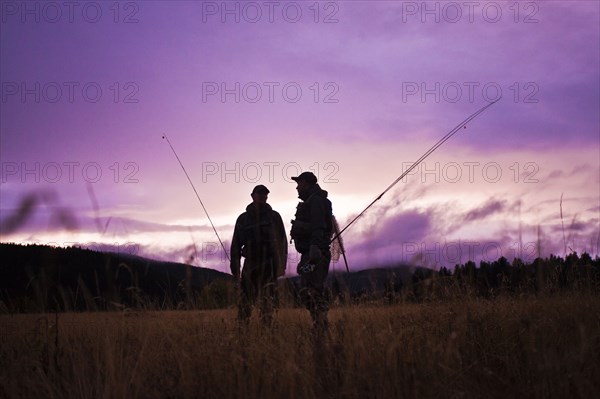 Caucasian men carrying fishing rods