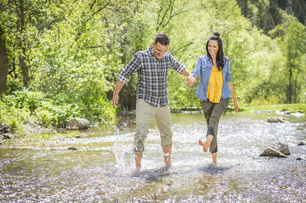 Woman kicking water on man in river