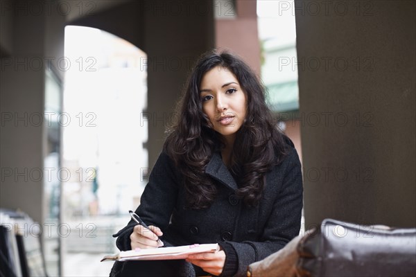 Middle Eastern woman writing in notebook