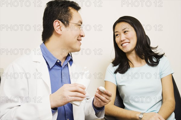 Asian male optometrist giving contact lenses to patient