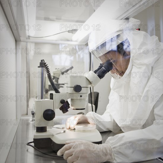 Middle Eastern scientist in clean suit using microscope