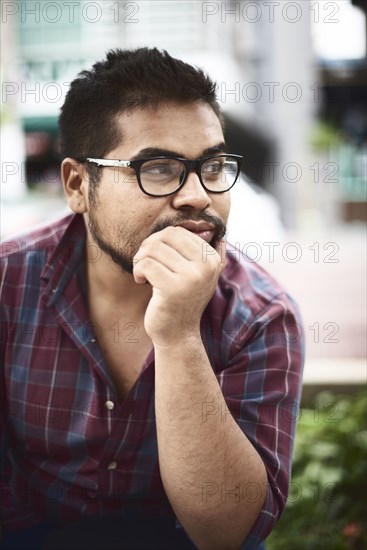 Pensive Hispanic man with hand on chin