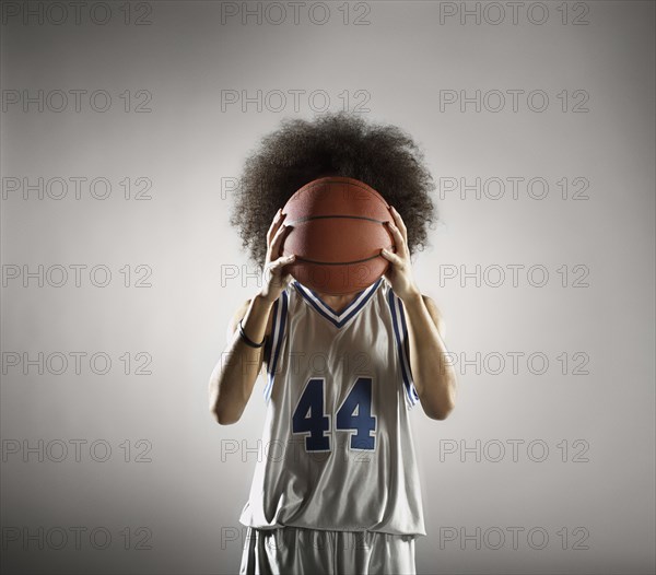 Mixed race basketball player holding basketball