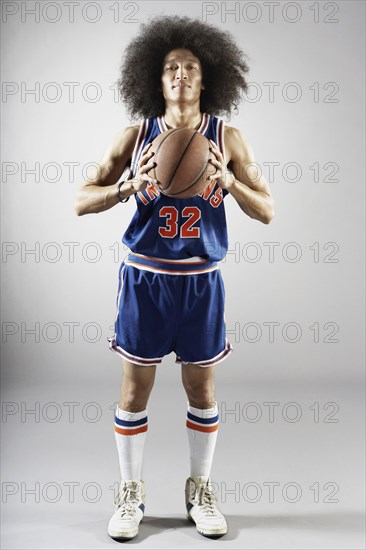 Mixed race basketball player holding basketball