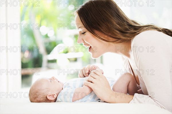 Caucasian mother playing with baby on changing table