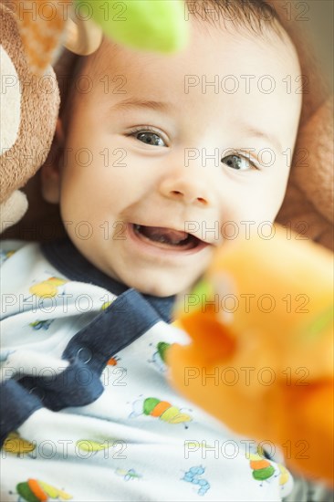 Mixed race baby laying under toys