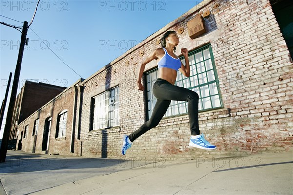 Black woman running on city street