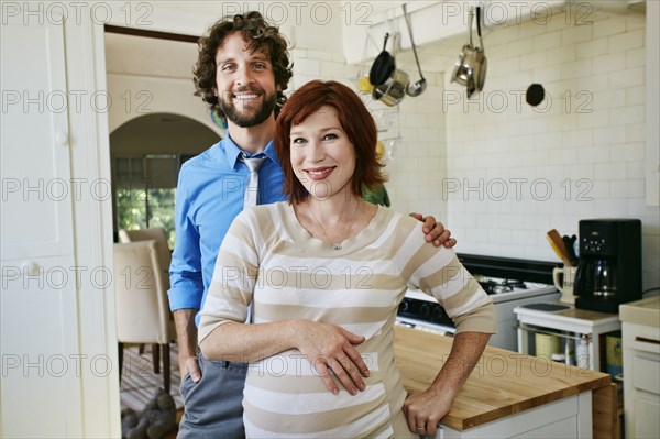 Pregnant Caucasian couple smiling in kitchen