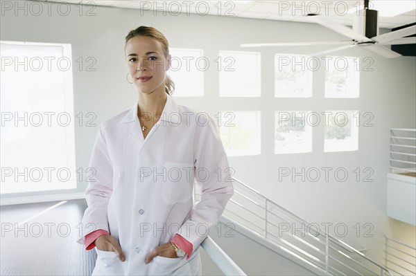 Caucasian doctor standing with hands in pockets near railing