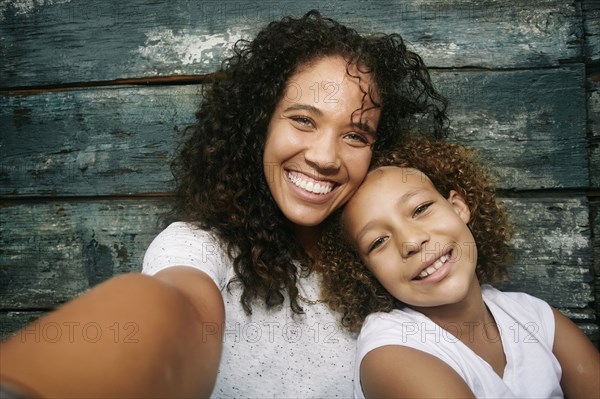 Mixed race mother and daughter taking selfie