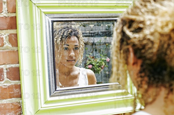 Reflection of serious Mixed Race woman in mirror