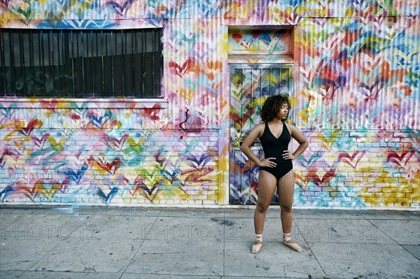 Mixed race ballet dancer resting on sidewalk