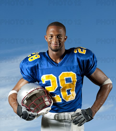 Black football player holding helmet