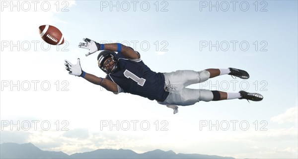 African American football player catching ball