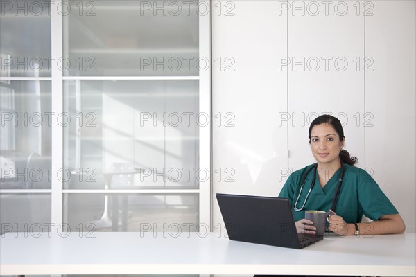 Mixed race doctor using laptop