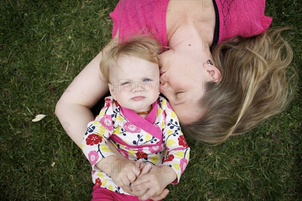 Caucasian mother and daughter laying in grass