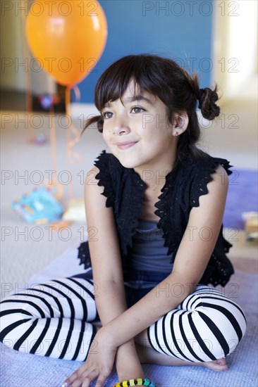 Mixed race girl sitting on floor at party