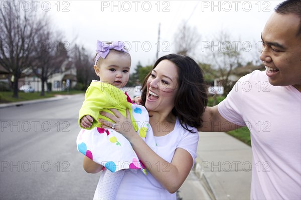 Mother and father standing outdoors with baby girl