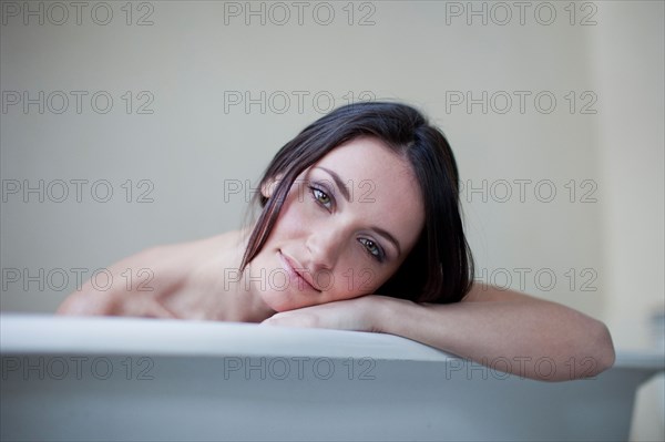 Caucasian woman leaning on side of bathtub