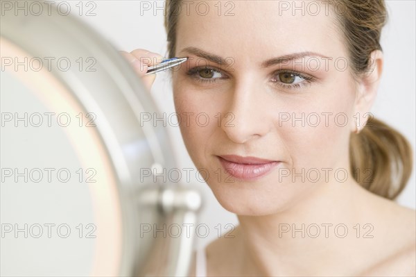 Hungarian woman tweezing eyebrows