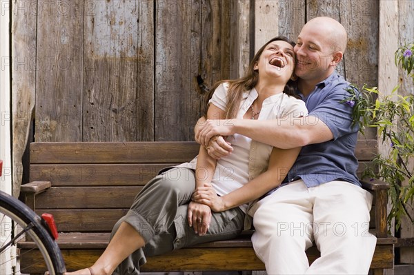 Laughing couple hugging on bench