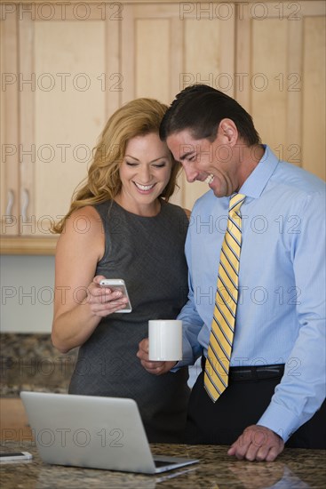 Caucasian couple using cell phone at breakfast