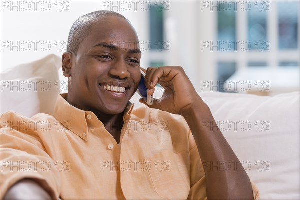 Black man talking on cell phone on sofa