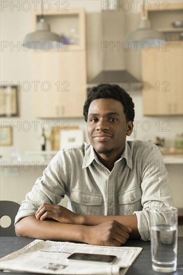 Black man reading newspaper at breakfast table