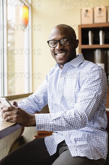Black man using cell phone in coffee shop