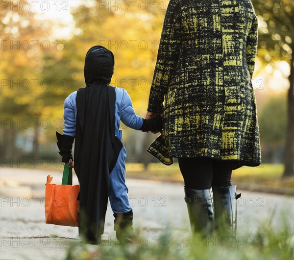 African American boy trick-or-treating with mother on Halloween