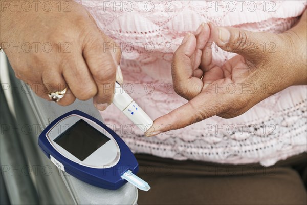 Senior African American woman testing blood sugar