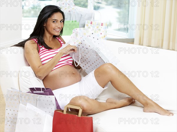 Pregnant Hispanic woman opening gifts