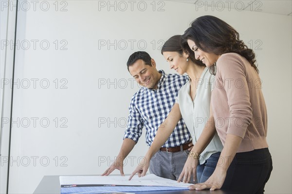 Business people examining blueprints in office